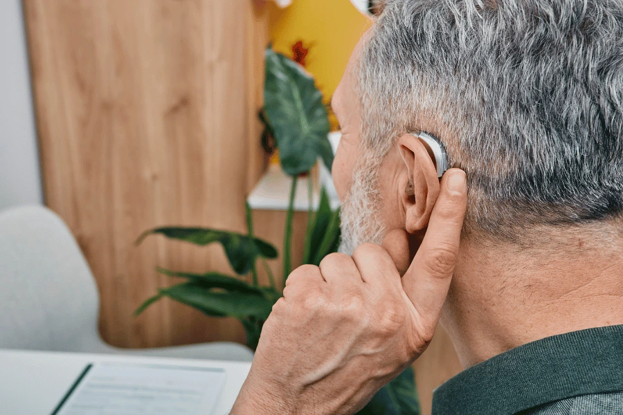Man wearing a behind-the-ear hearing aid at home during a trial period